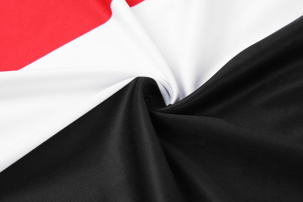 A fabric featuring red, white, and black sections, showcasing a smooth and flexible texture. The fabric has a slight sheen.