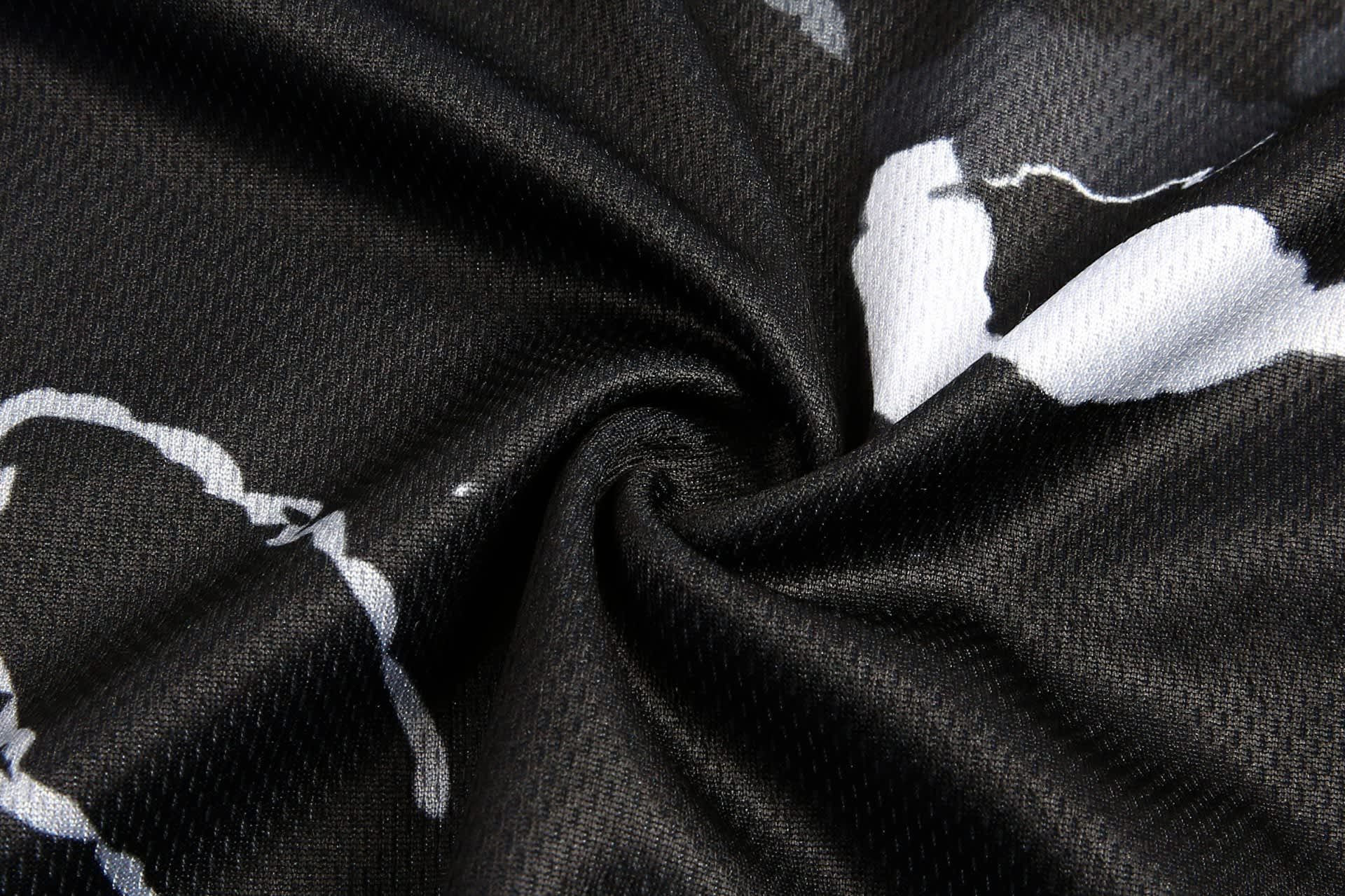 A close-up of a black fabric with a white abstract pattern, featuring a smooth, textured surface and branding.
