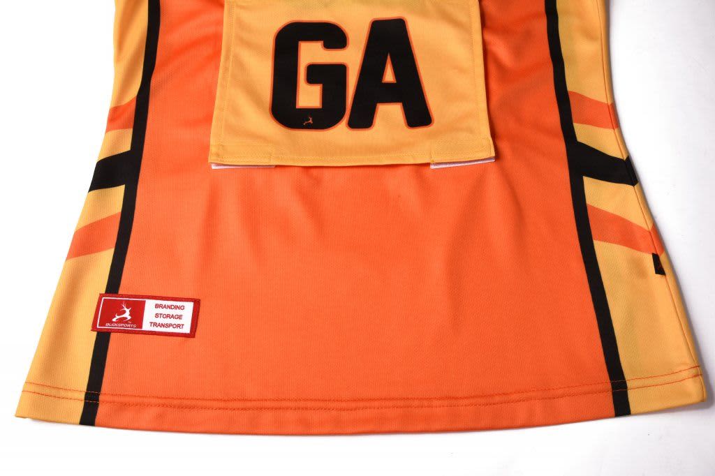 An orange netball polo featuring black accents and a logo, designed with a sleek fit and team identification.