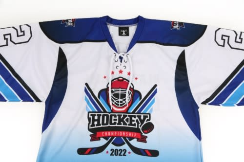 A blue and white ice hockey jersey featuring a logo and design related to the sport, with a prominent graphic on the front.