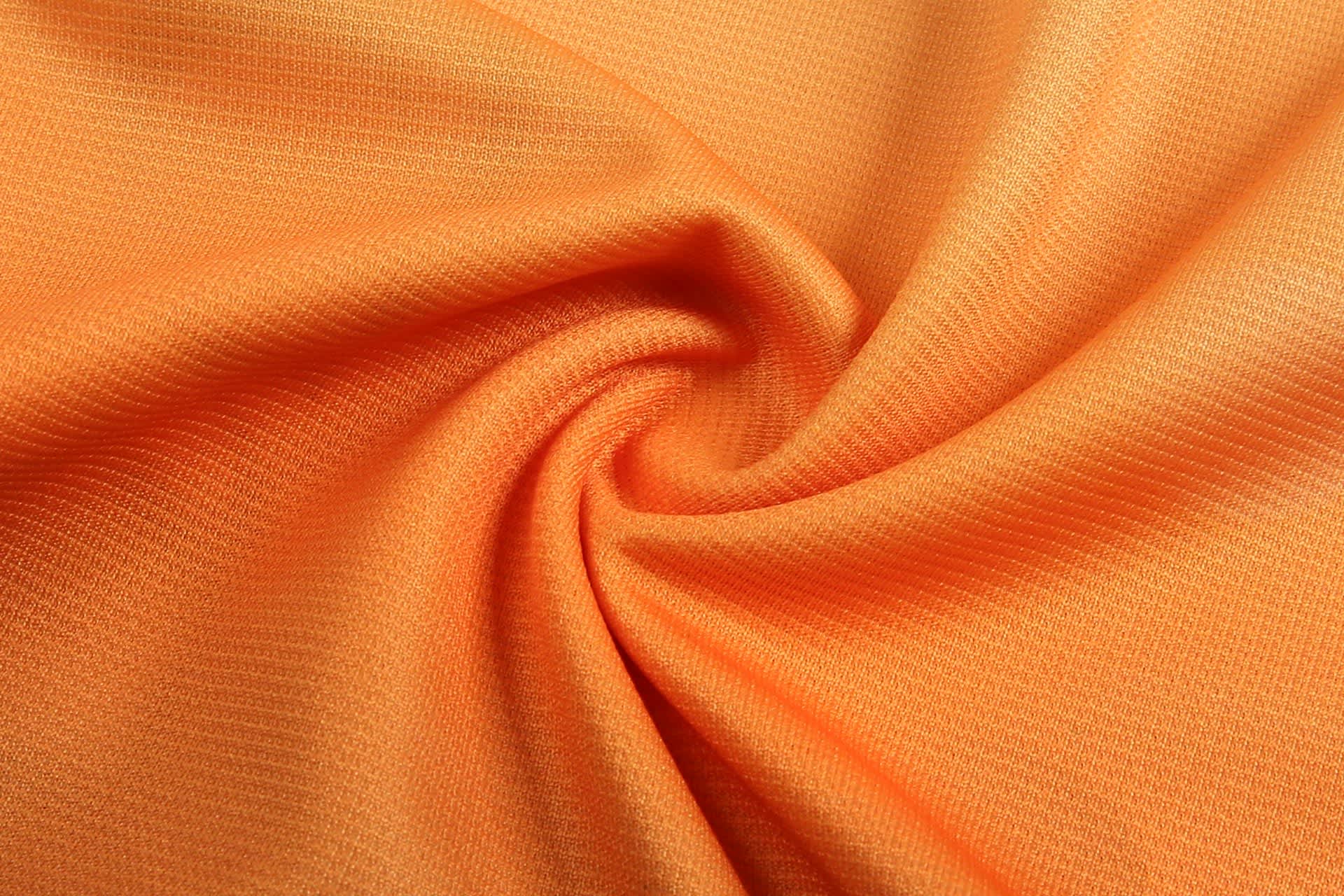 A swirl of bright orange fabric, featuring a textured pattern. The material appears lightweight and smooth.