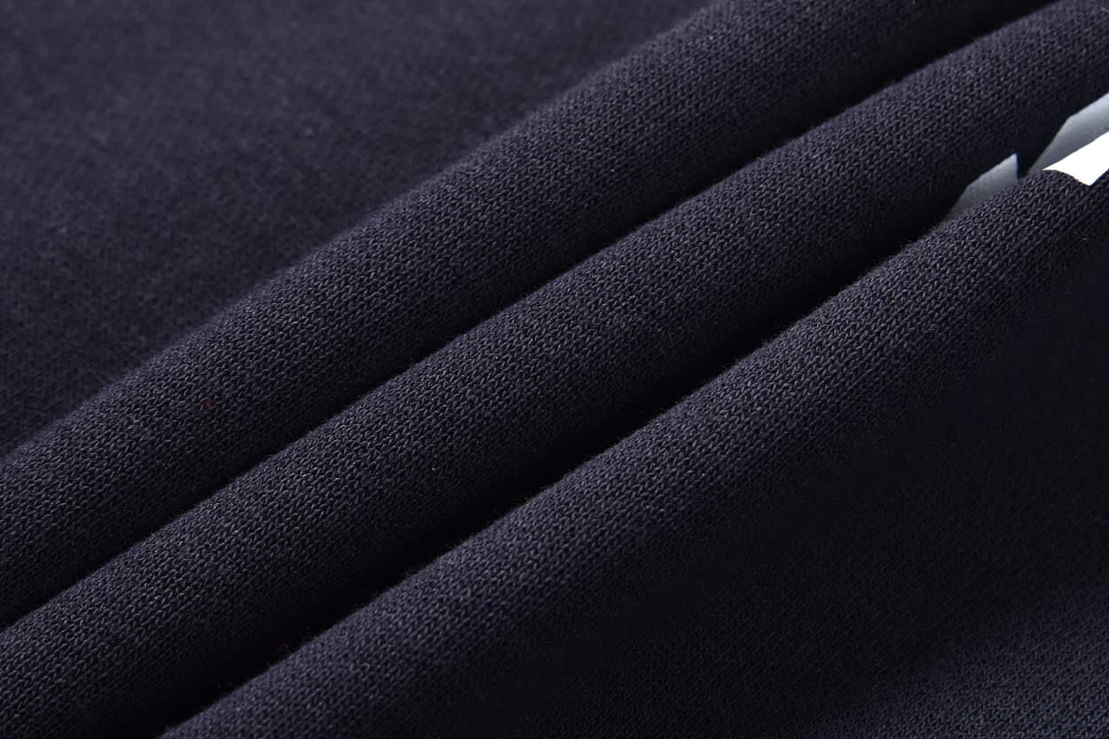 A close-up of a dark navy fabric with a smooth texture, featuring multiple folded layers. It has a subtle sheen.