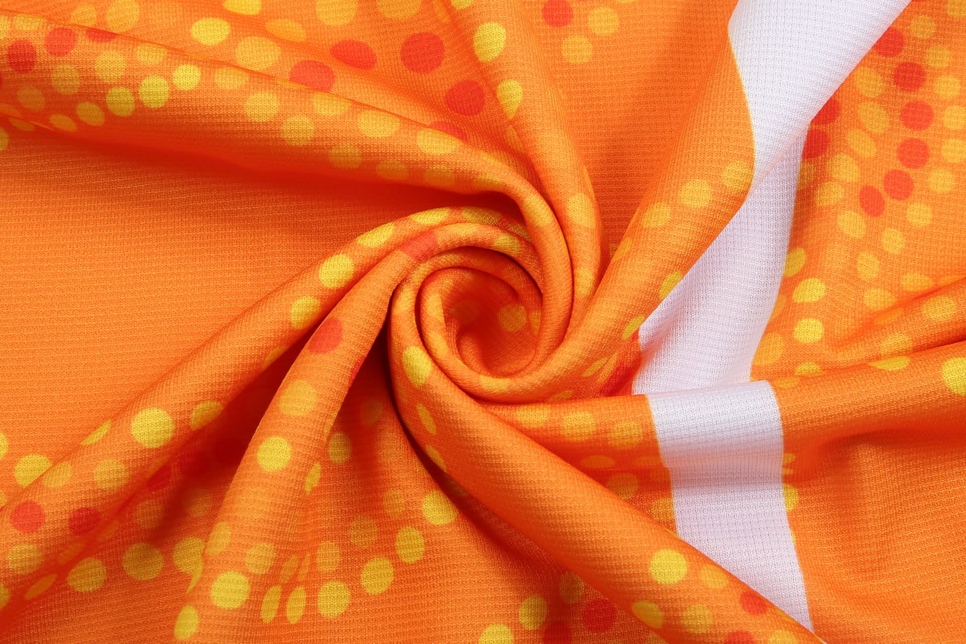 A vibrant orange fabric with yellow and red circular patterns, featuring a smooth, swirling texture.