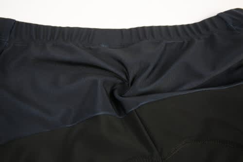 A close-up view of a cycling jersey featuring a dark navy and black design, with a logo on the back.