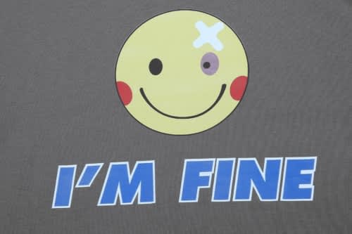 A grey T-shirt featuring a smiley face graphic with a bandage and the text "I'M FINE" in blue.