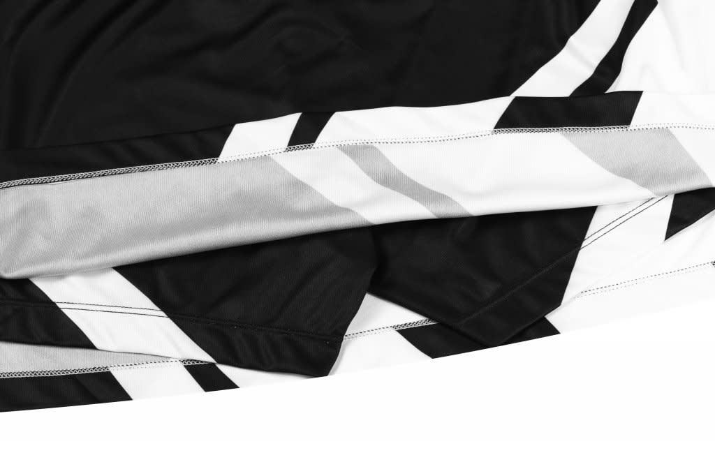 A black and white sports jersey with a geometric design and a logo on the fabric.