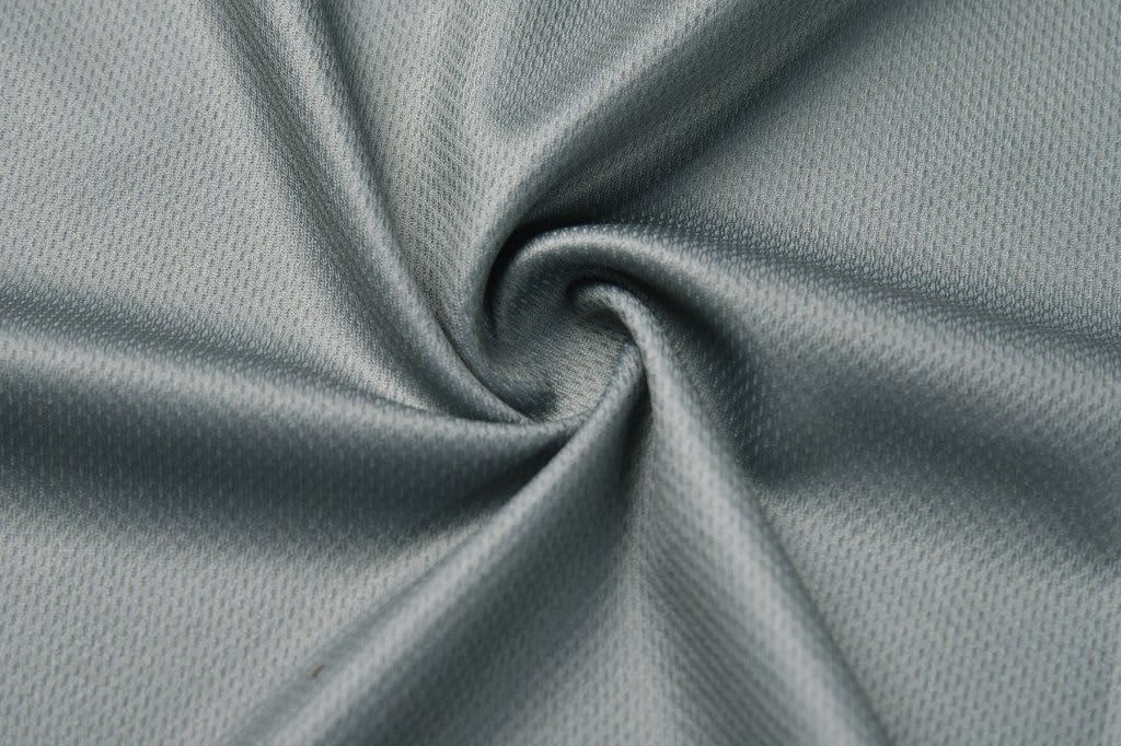 A swirl of light grey fabric, showcasing a smooth, textured surface. The material appears soft and flexible.