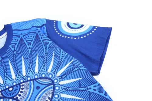 A blue T-shirt featuring intricate patterns in various shades of blue, with a branding logo present.