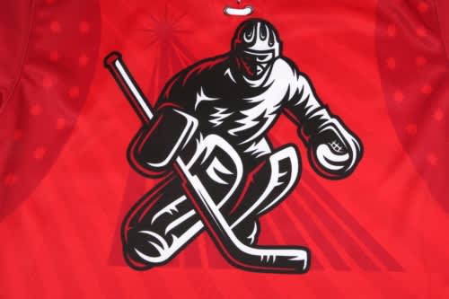 A red hockey jersey featuring a graphic of a player in action with a stick and puck. Includes a logo.