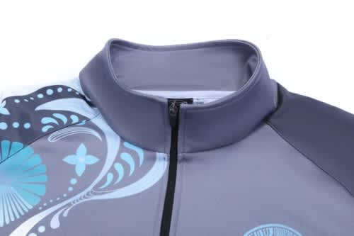 A school wear jacket in grey with blue patterned designs and a zippered collar. It features a logo on the front.