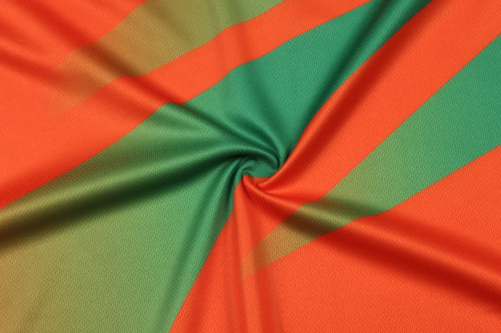 A fabric featuring bold orange and green stripes, with a smooth texture. The material has a slight sheen.