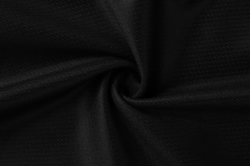 A close-up of black mesh fabric with a textured pattern, spiralling inwards.
