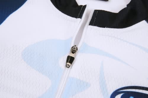 A close-up of a white and blue cycling jersey featuring a zip and a logo. The fabric appears textured.