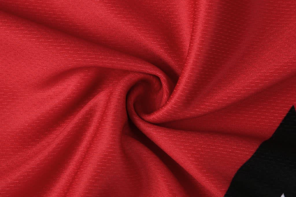 A red and black fabric material, with a textured pattern, twisted to show its softness and flexibility.