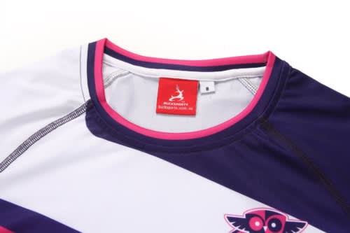 A white and navy sports jumper with pink accents, featuring a logo and a tag at the neckline.