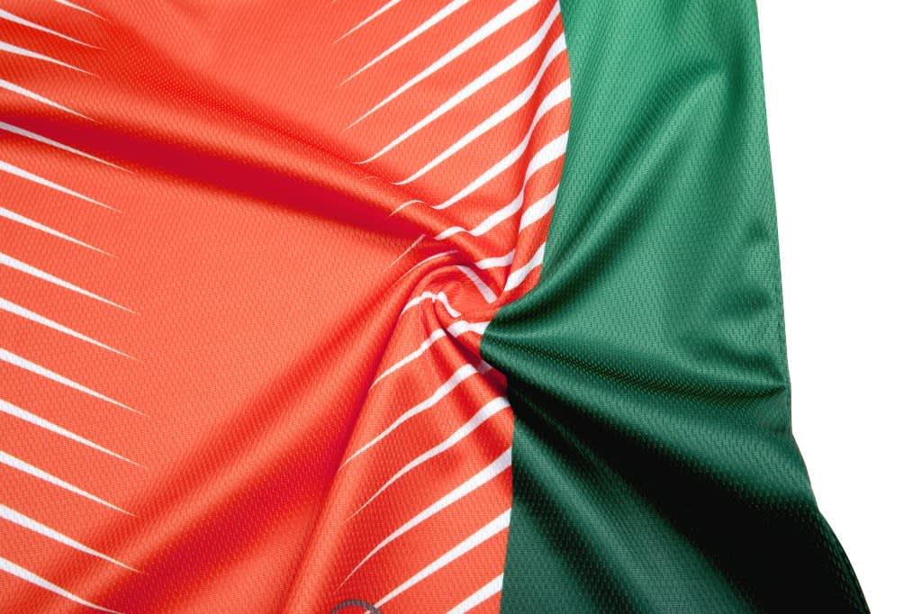 A custom esports T-shirt featuring an orange and green design with white stripes. It has a logo on it.