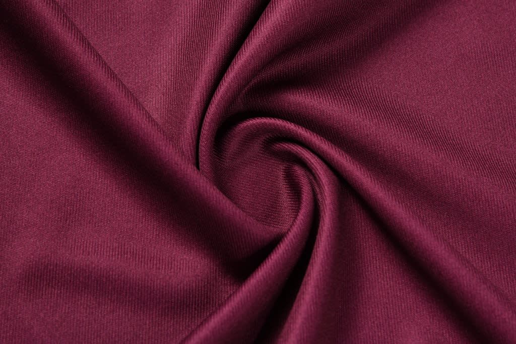 A deep burgundy fabric in a swirling pattern, showcasing a smooth texture. The image features a logo.