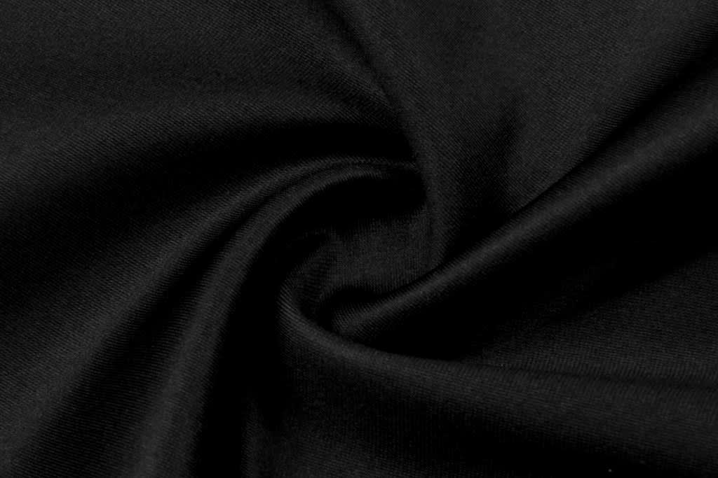 A close-up view of black fabric, showcasing a smooth texture and a swirling pattern.