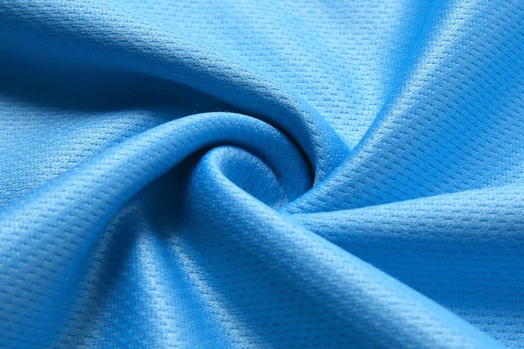 A close-up of a blue, textured fabric showcasing a smooth, breathable material.
