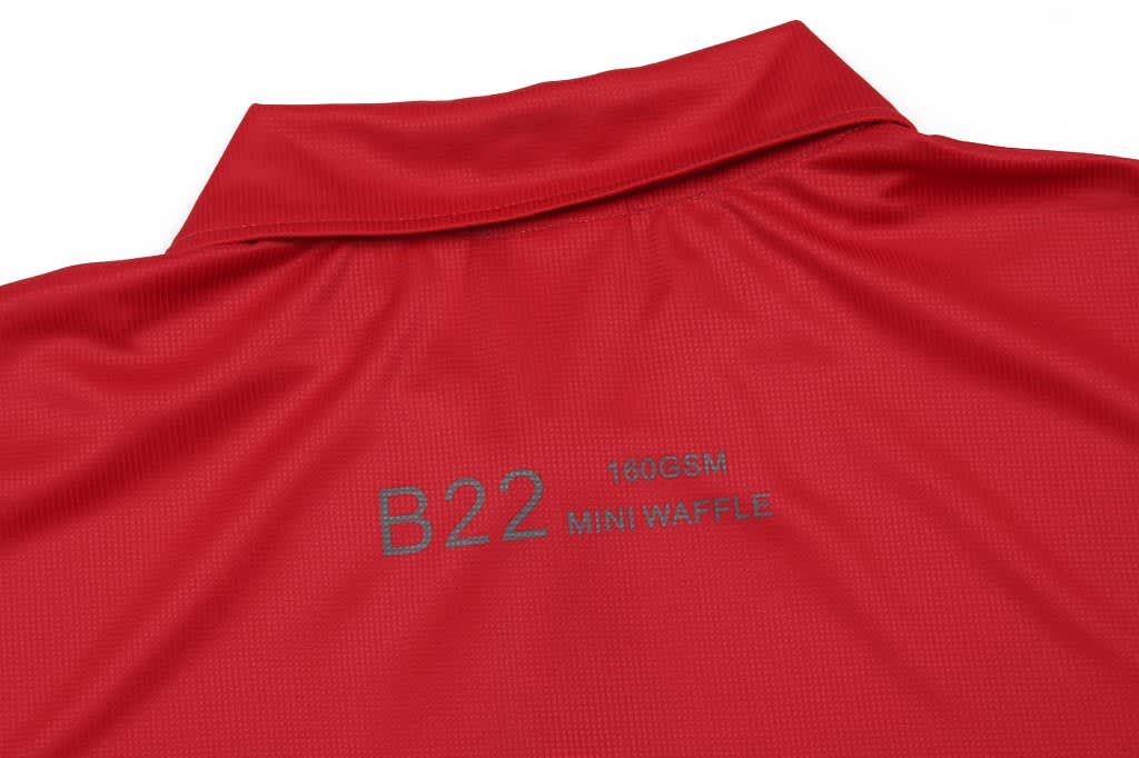 A red polo shirt with a collar and a textured mini waffle pattern on the fabric. It has branding on the back.