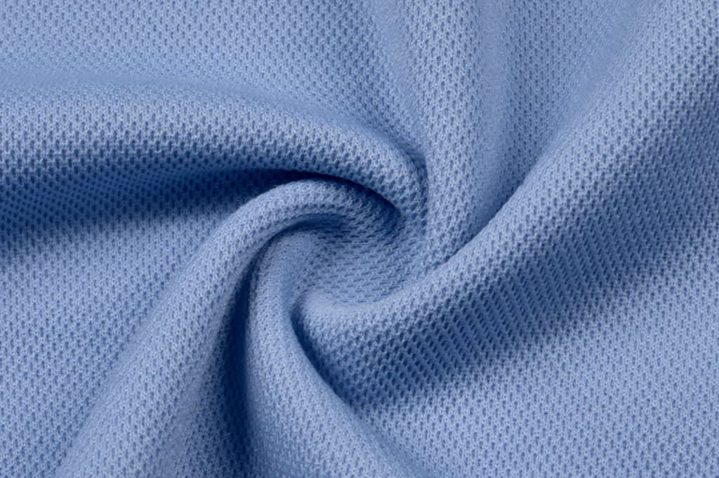 A close-up of light blue textured fabric, displaying a soft, woven pattern suitable for apparel.