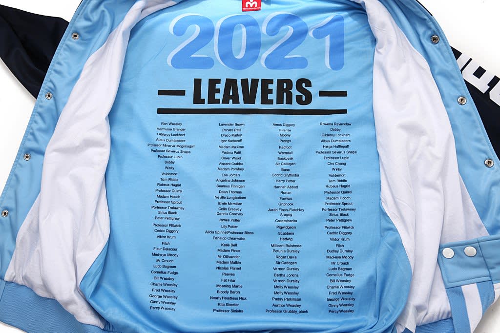A light blue leavers jacket with names printed inside, featuring a logo and a blue and black outer design.