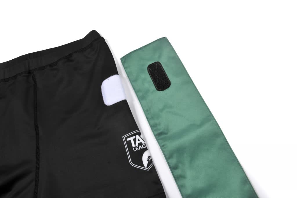 Black shorts with a white patch and a green side panel, featuring a logo.