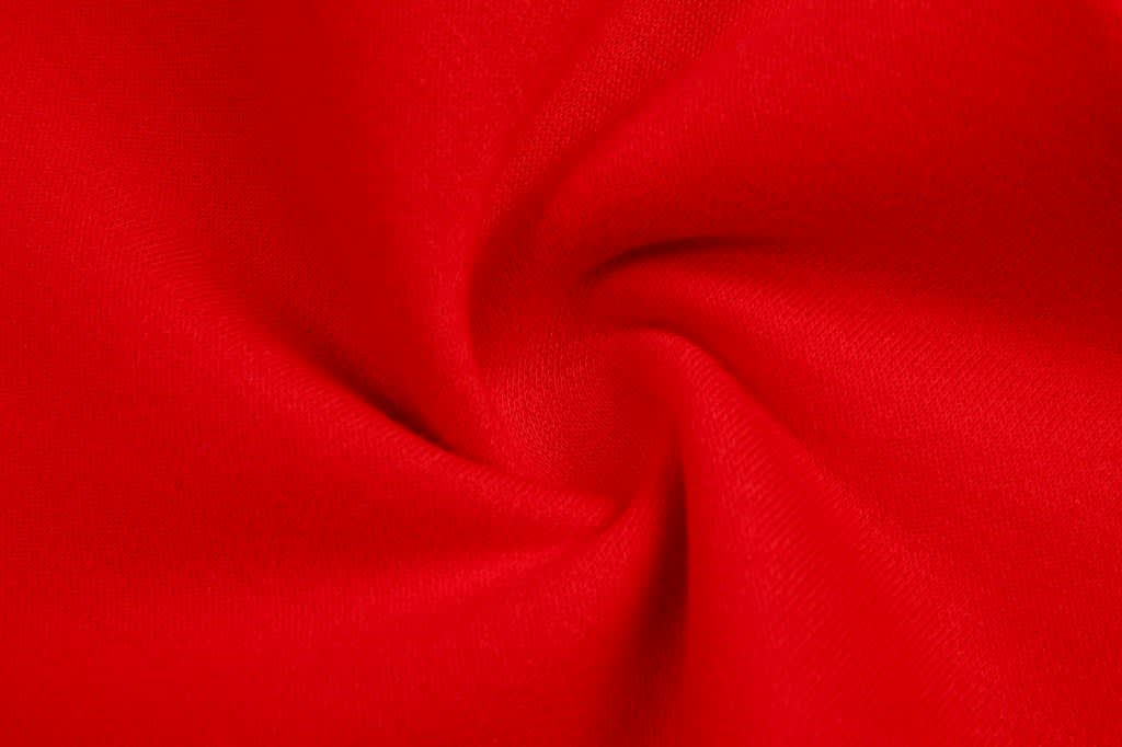 A red fleece fabric displaying a smooth, twisted texture. The material is soft and durable.