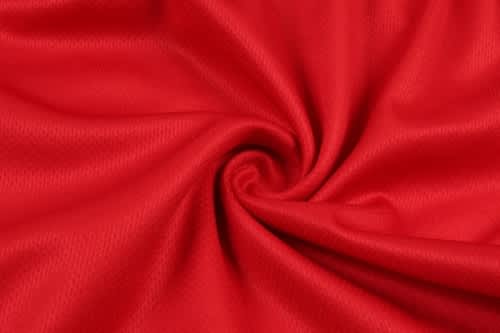 A red fabric in a swirling pattern, suitable for sports uniforms or jerseys, featuring a smooth texture.