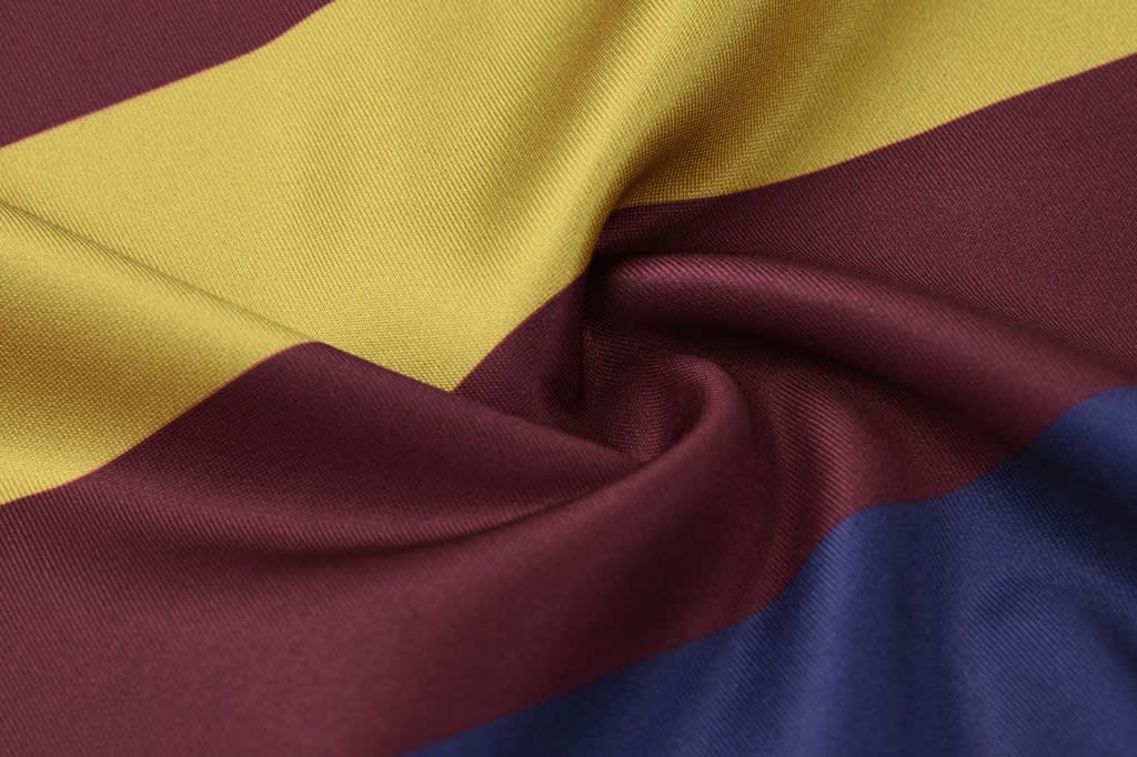 A close-up view of a fabric featuring burgundy, yellow, and blue horizontal stripes with a smooth texture.