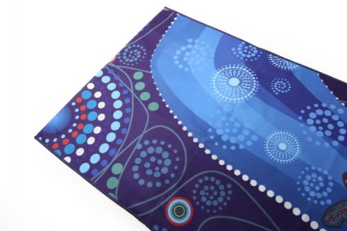 A spread towel featuring vibrant blues and purple patterns, decorated with dot motifs and swirls. It has a logo.