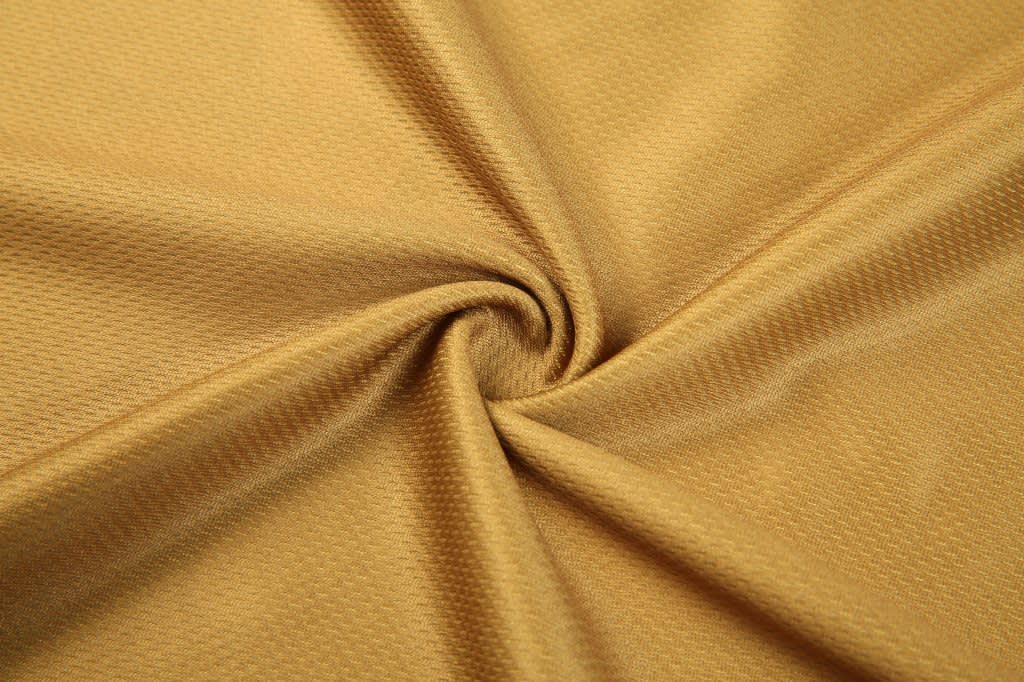A silky, golden fabric with a textured pattern, showcased in a swirling arrangement.