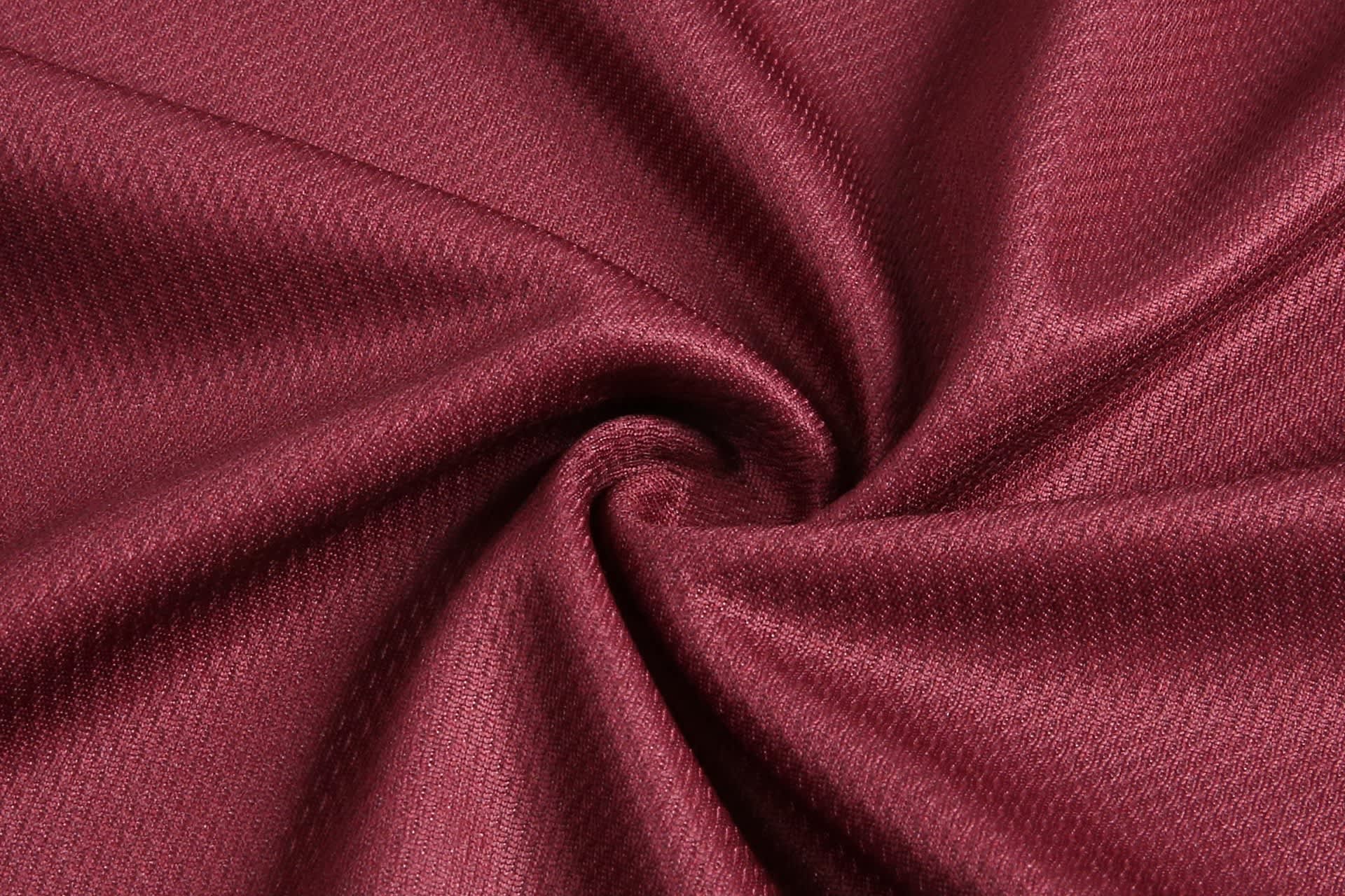 A burgundy fabric with a textured pattern, arranged in a swirl. The fabric appears smooth and lightweight.