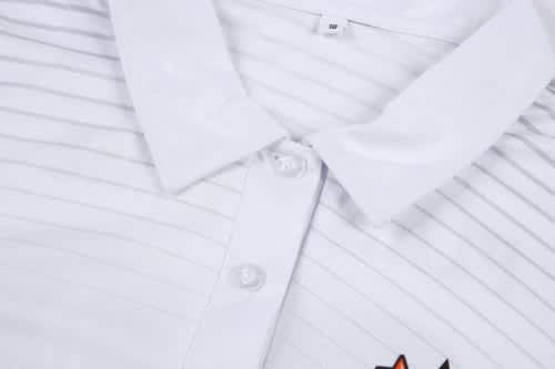 A white cricket uniform jersey featuring textured stripes and a collar, complete with a logo on the front.
