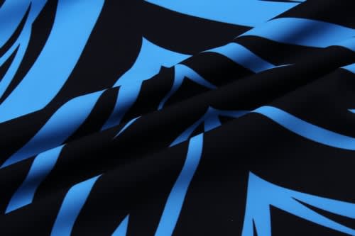 A close-up of fabric featuring a bold black background with vibrant blue leaf-like patterns.
