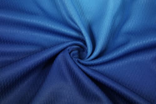 A swirling fabric with a gradient of blue shades, suitable for sports uniforms and jerseys. It has a textured pattern.