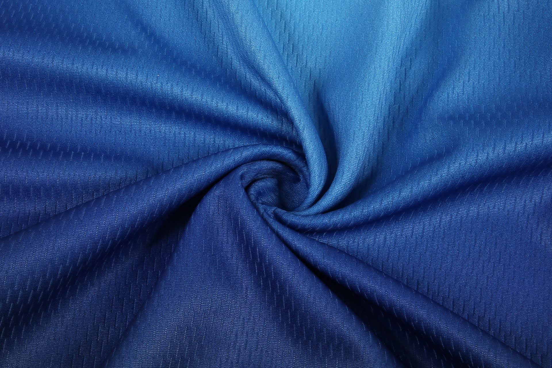 A jersey fabric in shades of blue, showcasing a textured, swirling pattern, suitable for a soccer uniform.