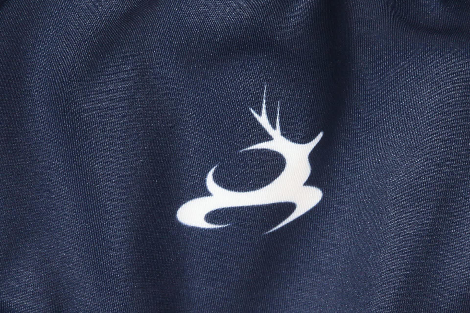 A dark blue track suit warm-up featuring a white logo. The fabric appears smooth and sporty, suitable for athletic wear.