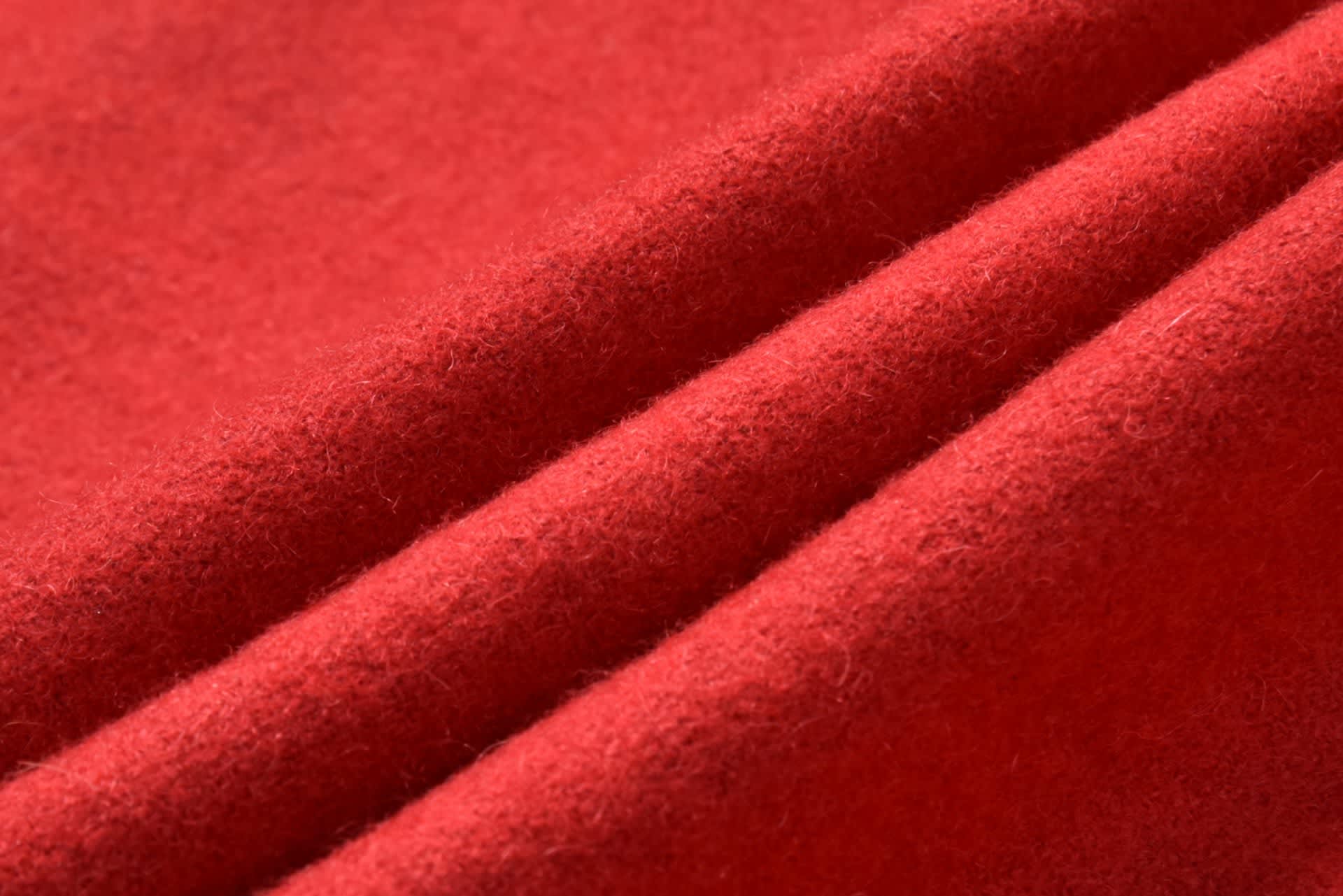 A close-up of red fabric with a soft, textured appearance, featuring folded layers.