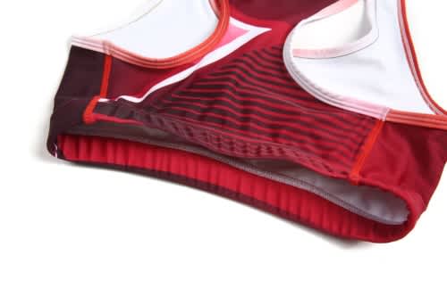 A red sports jersey with white and dark red accents, featuring a logo and a ribbed bottom hem.