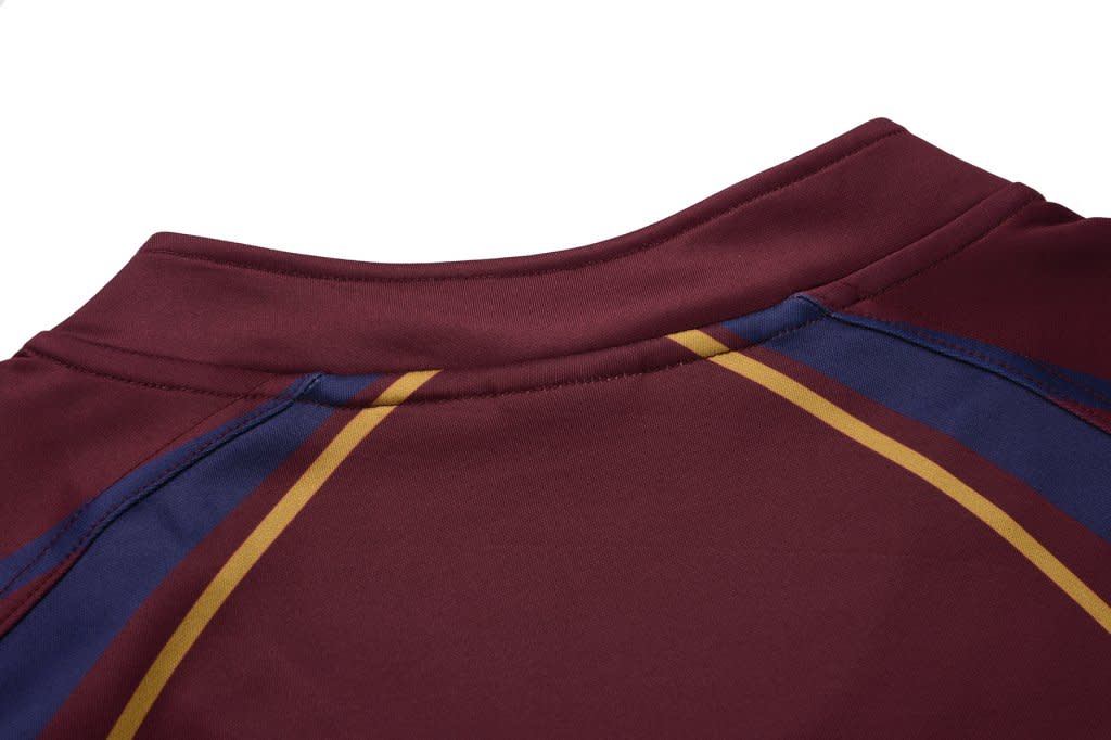 A maroon rugby tee featuring blue and gold stripes on the shoulders and a logo on the back.