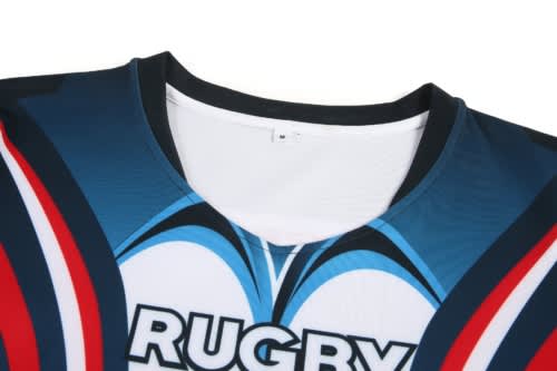 A close-up of a blue rugby jersey featuring red and white accents, with a logo on the front.
