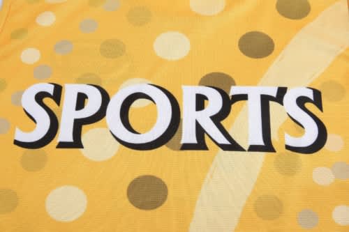 A yellow sports jersey with a dotted pattern and a prominent logo featuring the word "SPORTS."