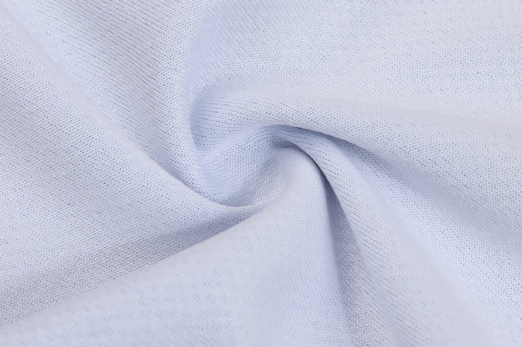 A fabric swatch featuring a light blue texture, showing a soft, knit pattern. It has a smooth finish and gentle drape.