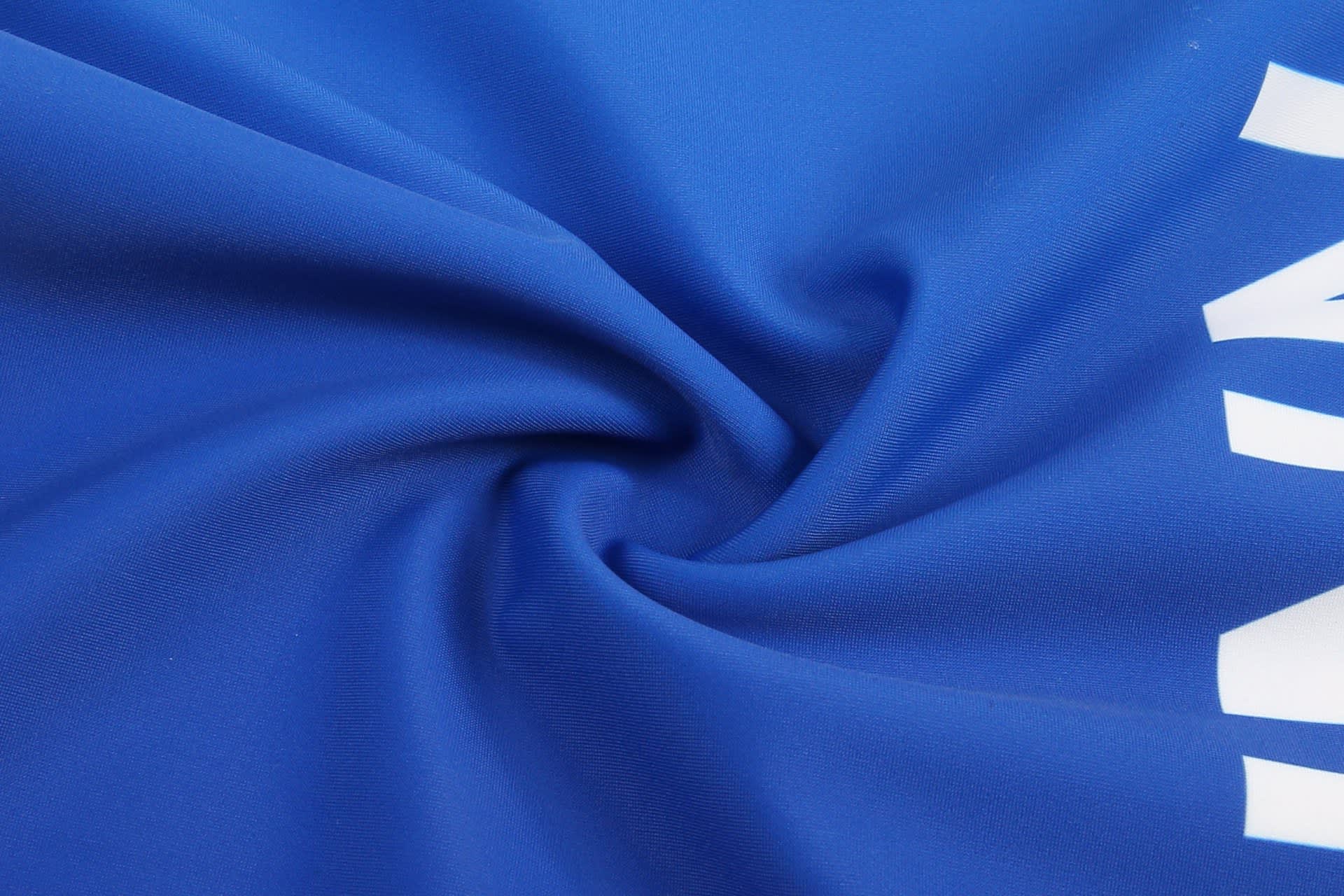A close-up of a blue fabric, featuring a smooth texture and a prominent white branding logo.