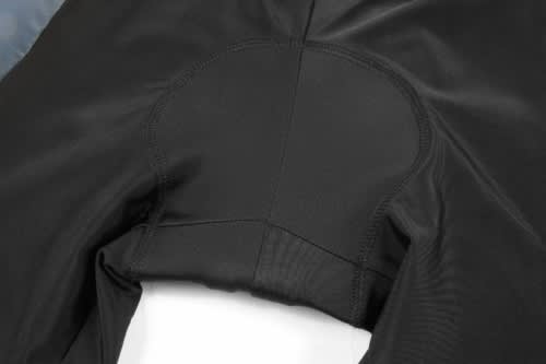 A close-up of a black cycling uniform featuring detailed stitching and an integrated chamois pad.