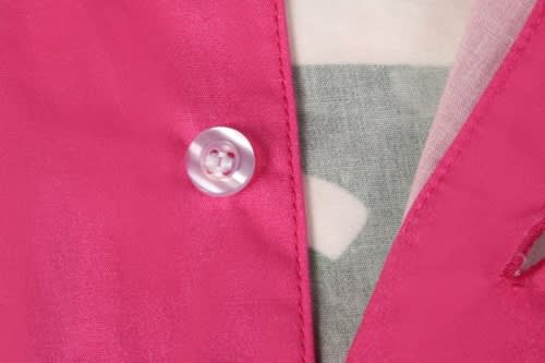 A close-up of a pink beach shirt with a button detail and part of a patterned fabric visible underneath.