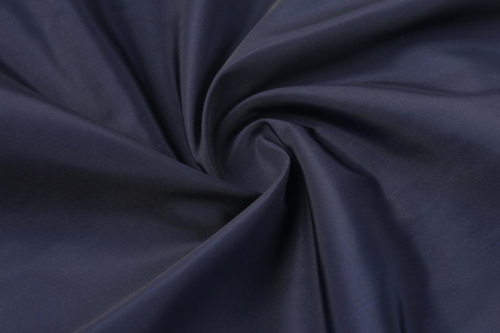 A close-up of navy fabric, featuring a smooth texture with a twisted pattern. The image includes branding elements.