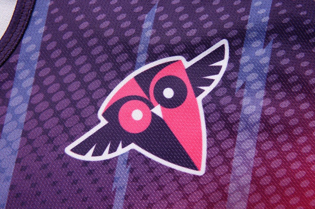 A purple and pink women's vest featuring a logo with an owl design. The fabric has a textured pattern.