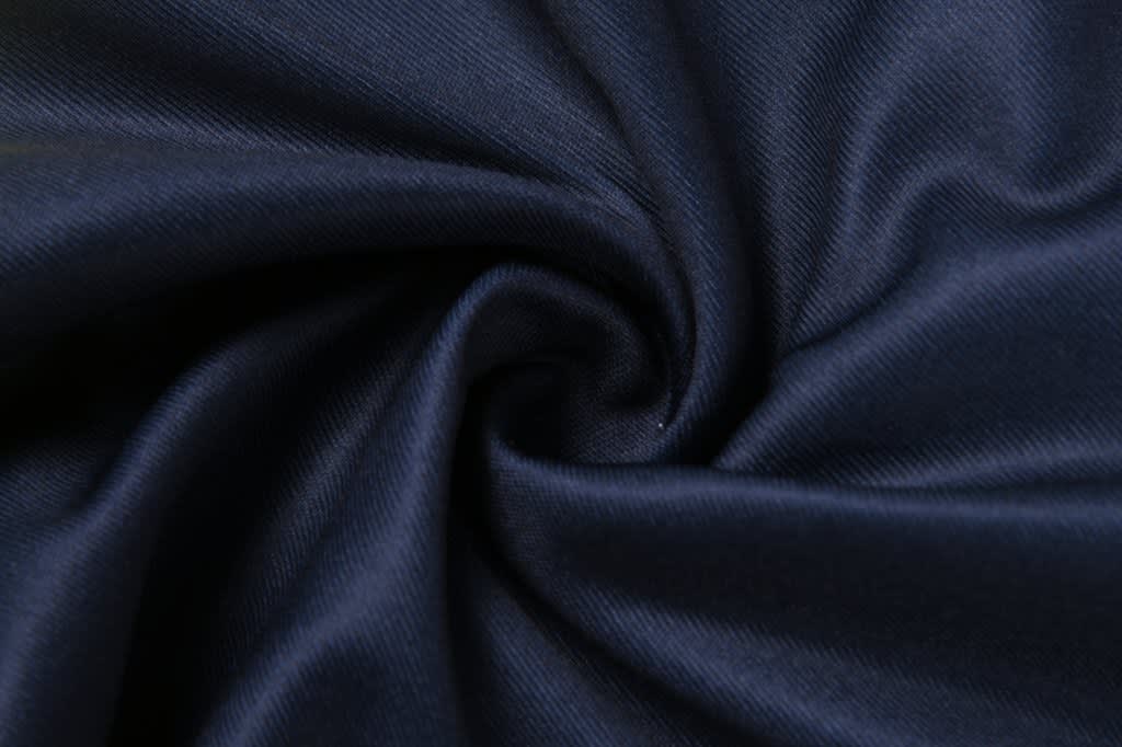 A swirl of dark navy fabric, showcasing a smooth and textured surface. Contains a branding logo.